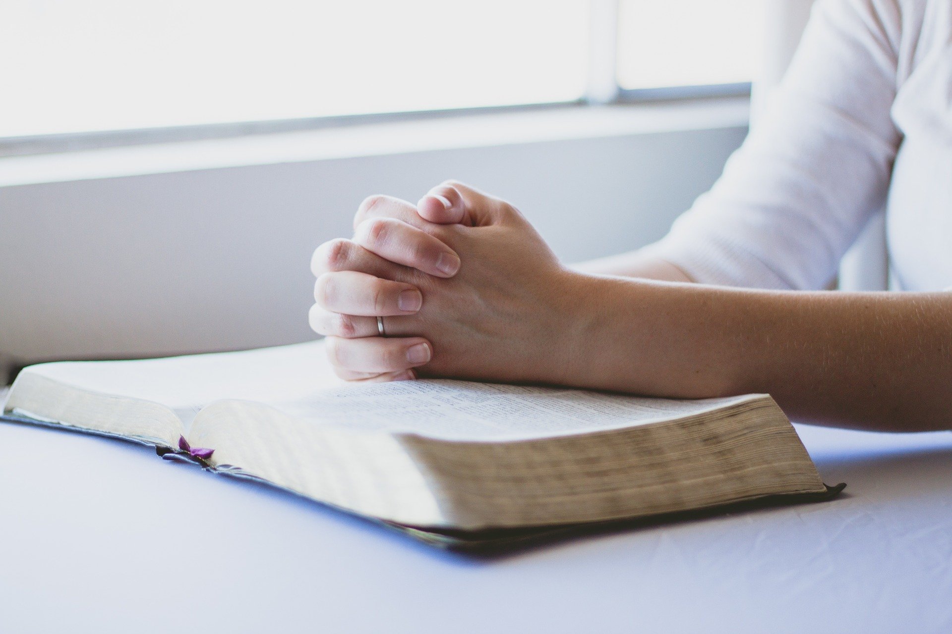 hands clasped on bible praying